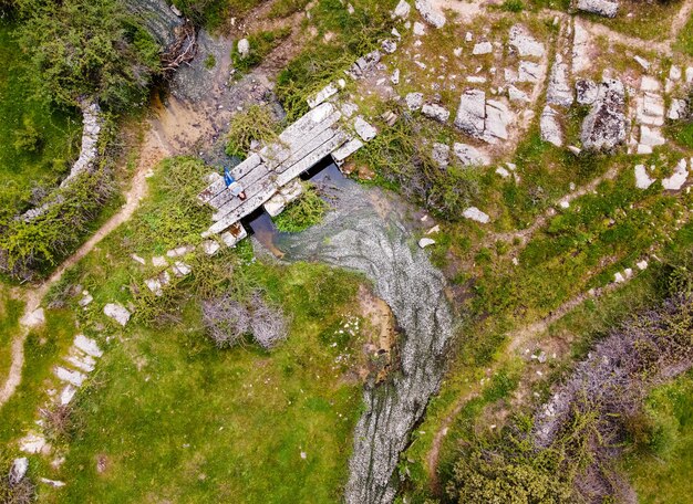 An aerial view of a dilapidated bridge in a rural area, with visible signs of decay and rust, needing repair or replacement, illustrating the urgent need for infrastructure investment.