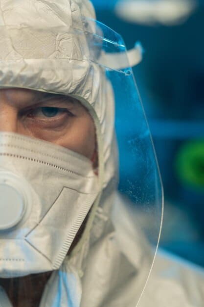 A close-up photograph of a technician in a cleanroom environment, wearing protective gear and examining air quality monitoring equipment. The setting is a modern laboratory with advanced technology, emphasizing the importance of precise measurement and scientific analysis in complying with air quality standards.