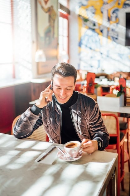 A person wearing headphones and watching a K-drama on their phone while sitting in a cafe, with Korean textbooks and notes visible on the table.