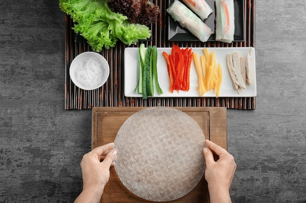 A step-by-step guide on how to roll Kimbap, showing each layer of ingredients (rice, vegetables, meat, egg) being carefully placed on a sheet of seaweed, followed by the rolling process.