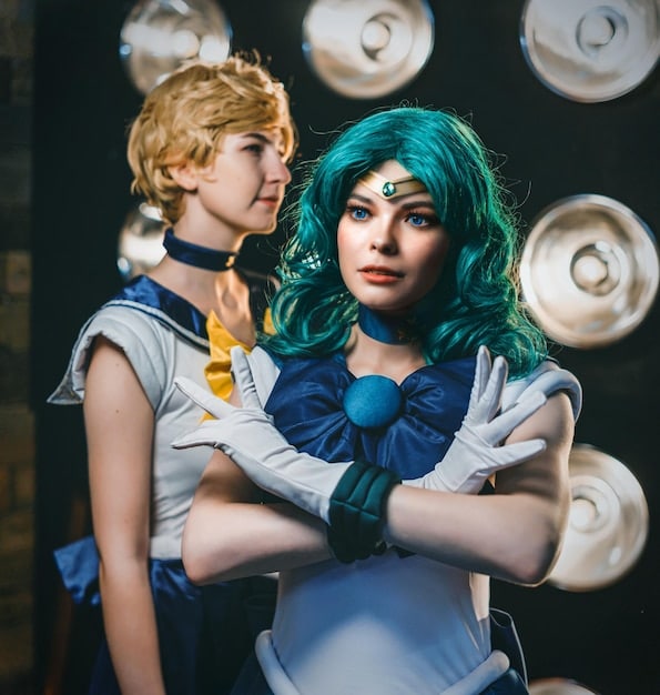A close-up shot of two cosplayers at an anime convention, showcasing intricate costume details and vibrant colors, with a blurred background of other attendees and convention booths.