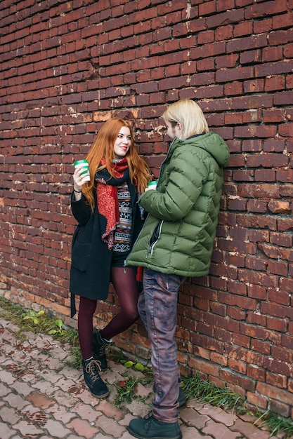 A photograph of a group of teenagers in the 1990s wearing grunge fashion, including flannel shirts, ripped jeans, and Doc Martens boots. They are standing in front of a brick wall with graffiti.